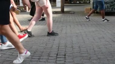 Erkekler ve kadınlar güneşli bir günde kaldırımda yürüyorlar.