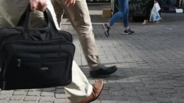 yürüyen bir iş çantası ile erkek, durur ve kaldırımda tekrar yürümek