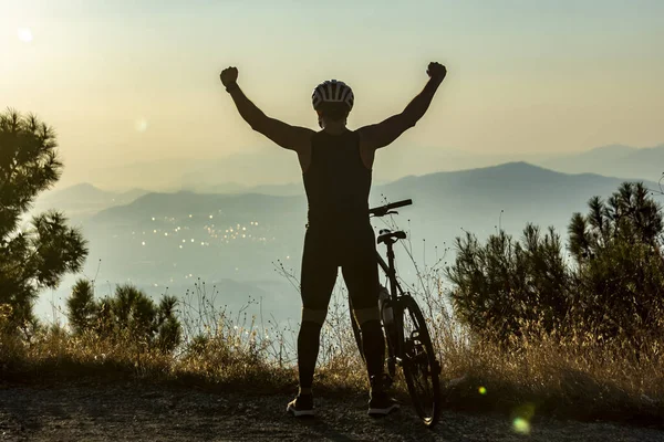 Silhouette of male biker raising hands for victory Stock Photo
