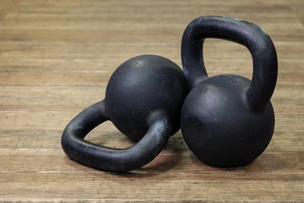 Due Pesanti Kettlebell Neri Fondo Legno — Foto Stock