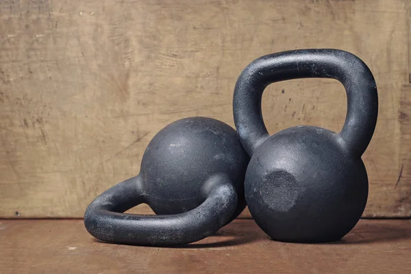 Due Pesanti Kettlebell Neri Fondo Legno — Foto Stock