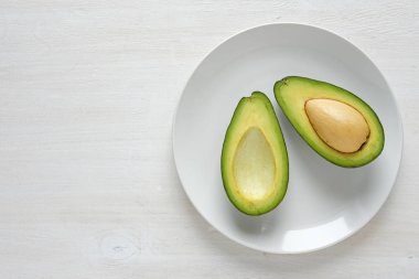 Sağlıklı, yeşil avokado ile beyaz bir arka plan ve kopya yer beyaz tabakta ikiye böldüm.