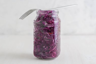 Lezzetli mor fermente lahana beyaz arka plan üzerinde duran çatal ile cam kavanoz