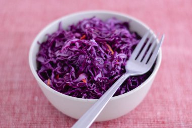 Seramik kase lezzetli mor fermente lahana mor zemin üzerine tam yatan çatal atış yukarıdan