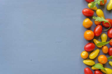 Kırmızı ve sarı domates ve yeşil hindiba bırakır yerleştirilmiş kopya alanı ile mavi yüzeyinde. Mutfak konsepti tarifi Malzemeler için