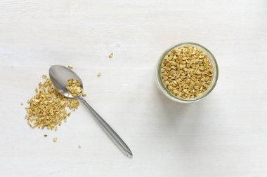Cam kavanoz kaşık ve tablo yüzey beyaz arka plan üzerinde küçük kazık ile yukarıdan izlendi kuru yulaf ezmesi