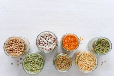 Cam kavanoz çeşitli kuru baklagiller tam mung fasulye, fasulye, mercimek ve üzerinde beyaz bir arka plan kopya alanı ile sağlıklı bir diyet bezelye