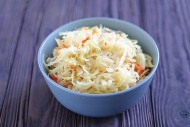 Ahşap masa üzerinde duran lezzetli fermente lahana seramik kase