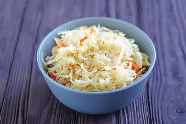 Ahşap masa üzerinde duran lezzetli fermente lahana seramik kase