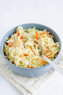 Nefis ile seramik kase görüntüsünü yukarıda fermente lahana ve beyaz zemin üzerine peçete üzerinde çatal duran