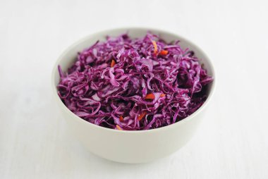 Yukarıda vuruşta seramik kase lezzetli mor fermente lahana beyaz arka plan üzerinde tam