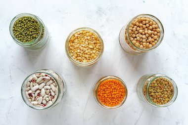 Beyaz arka plan, sağlıklı ve sağlıklı gıda kavramı üzerinde cam kavanozlara fasulye tohumları