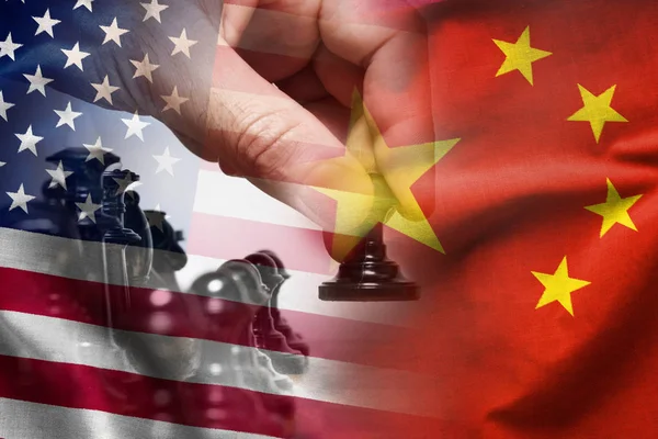 Composite of the Chinese and American flags with the hand of a chess player moving a pawn in a concept of politics, planning, strategy and discussion