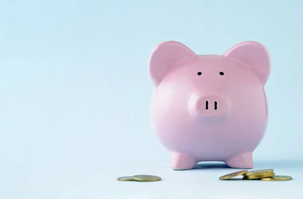 粉红小猪脸在蓝色背景与复制空间和分散硬币在前景在财务 投资和储蓄的概念 — 图库照片