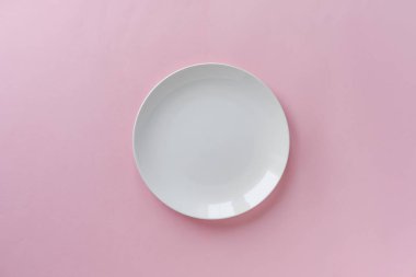 Tek boş temiz beyaz seramik tabak yemek üstten Bakınlan kopya alanı ile pembe bir arka plan üzerinde bir hizmet için