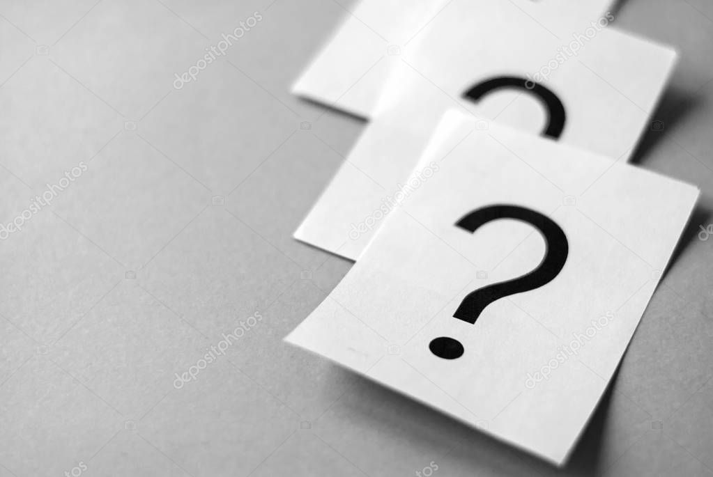 White cards with printed question marks on grey background with copy space. Queue of questions to be answer concept