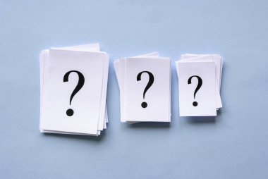 Üç soru işaretleri ile kağıt yığınları yığılmış