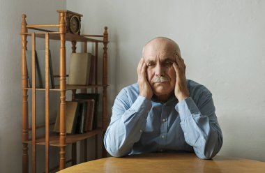 Worried elderly man with his head in his hands clipart