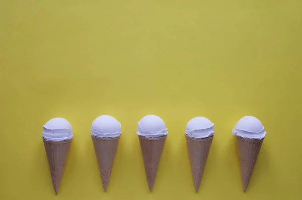 Row of vanilla ice cream cones on yellow — Stock Photo, Image