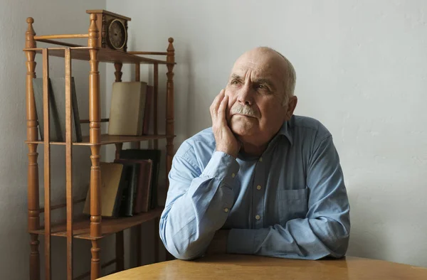 Senior man sitting deep in thought — Stock Photo, Image