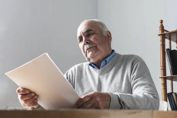 Starszy mężczyzna czytając papierowy dokument lub pismo — Zdjęcie stockowe