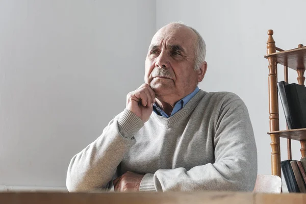 Пожилой человек с усами сидит и думает: — стоковое фото