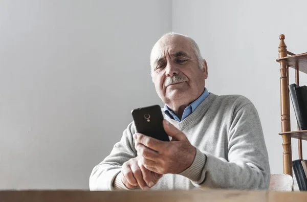 Senior man läser ett textmeddelande på en mobil — Stockfoto