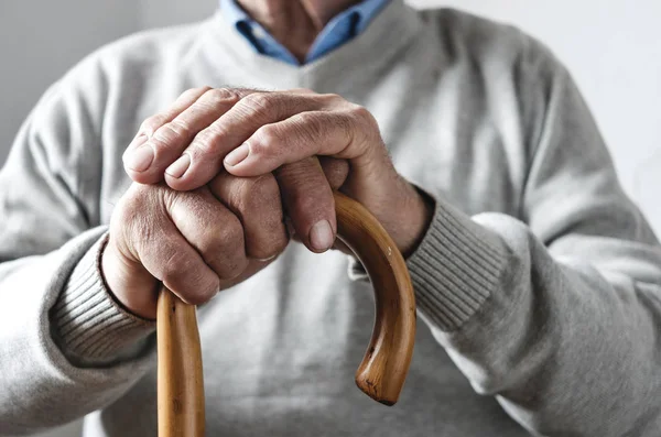 Hands of an elderly man resting on a walking cane — Stock Photo, Image