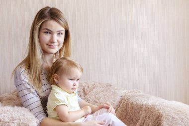 Genç anne ve kızı koltukta oturuyor.