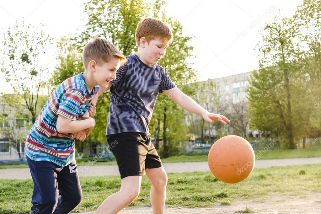 Two young boys chasing a basketball