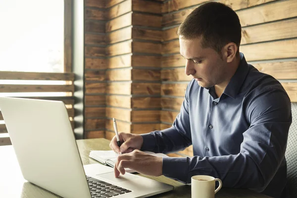 Jeune homme d'affaires prenant des notes de son ordinateur portable — Photo