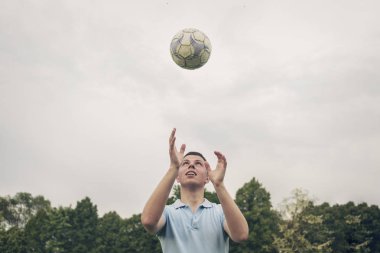 Genç adam havaya futbol topu atıyor.