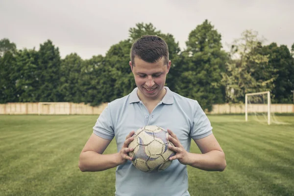 Bir futbol topu tutan gülümseyen genç adam — Stok fotoğraf