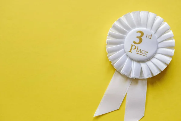 3rd place white ribbon rosette on yellow — Stock Photo, Image