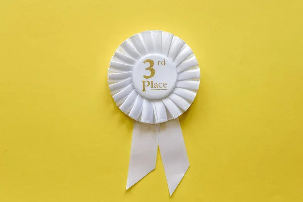 3o lugar roseta fita branca no amarelo — Fotografia de Stock