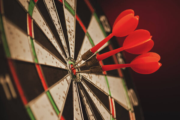 Three darts in the center bulls eye of a target