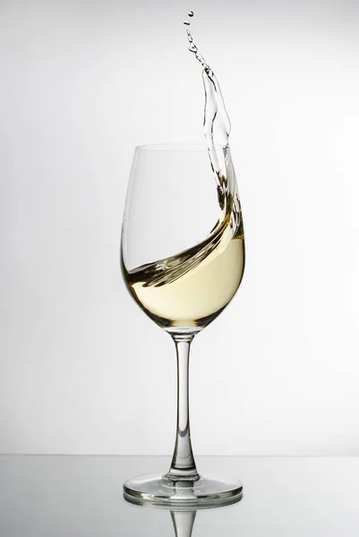 Vinho branco salpicando de um elegante copo de vinho — Fotografia de Stock