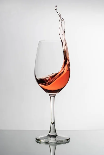 Vinho rosa salpicando para o lado de um copo de vinho — Fotografia de Stock