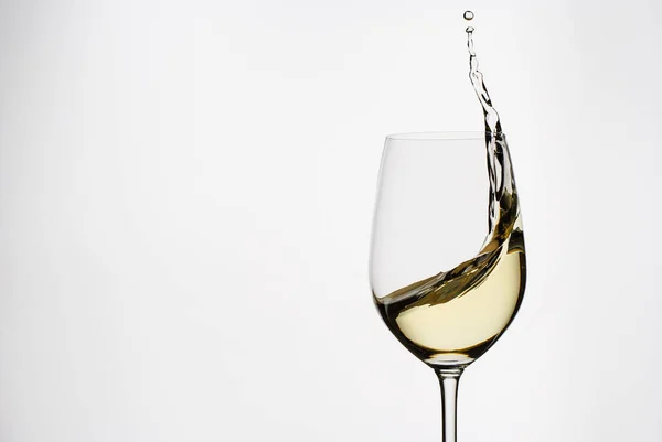 Vinho branco salpicando de um elegante copo de vinho — Fotografia de Stock