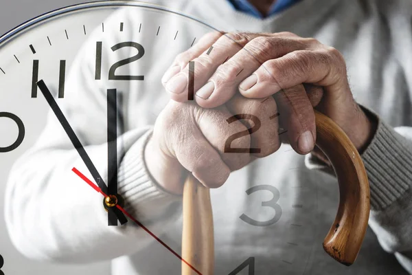 Manos de un anciano en un bastón sobre un reloj — Foto de Stock