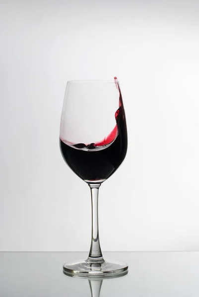 Vinho tinto salpicando para o lado de um copo de vinho — Fotografia de Stock