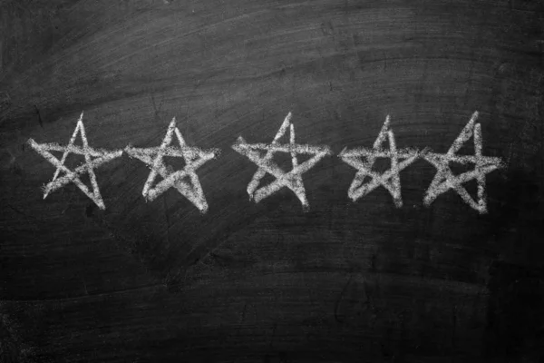 Five white chalk stars drawn on a blackboard