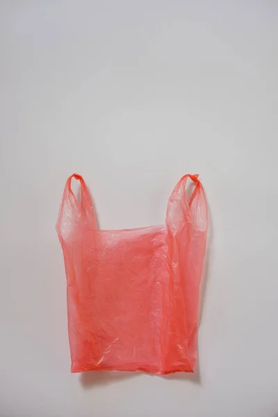 Смятый красный пластиковый пакет на сером — стоковое фото