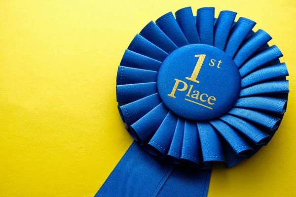 First Place Winners Rosette Blue Ribbon Gold Text Yellow Background — Stock Photo, Image