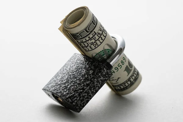 金融セキュリティの概念の白い背景に角度で休んで南京錠のシャンクを通ってねじ込まれたドル札のロール — ストック写真