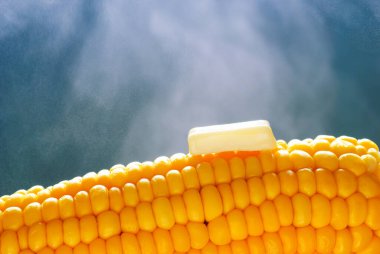 Buharda tereyağı eritmek mısır koçanını sağlıklı bir diyet konseptinde sarı çekirdeklere yaklaştırdı.