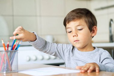 Çocuk eline bir kalem aldı ve çocukların resimlerini kağıda çizdi..