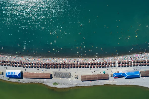 Sahilde kum üzerinde üst hava görünümünü tükürmek. Satır şemsiye ve şezlong, sıcak mavi deniz ve tatil vericiler eğleniyor. Kopya alanı