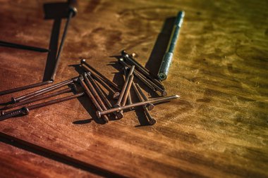 Güneşteki tahta masadaki çiviler ve vidalar