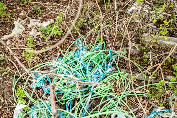 Green plastic electric cable protection thrown into the grass, p — Stock Photo, Image